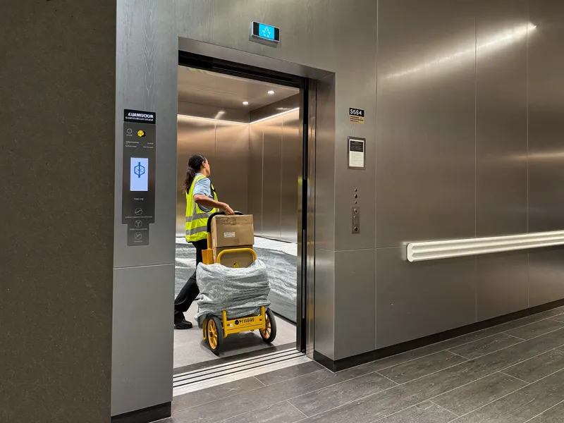 Movers pushing a dolly of boxes into a blanket-lined service lift in a Marina high-rise